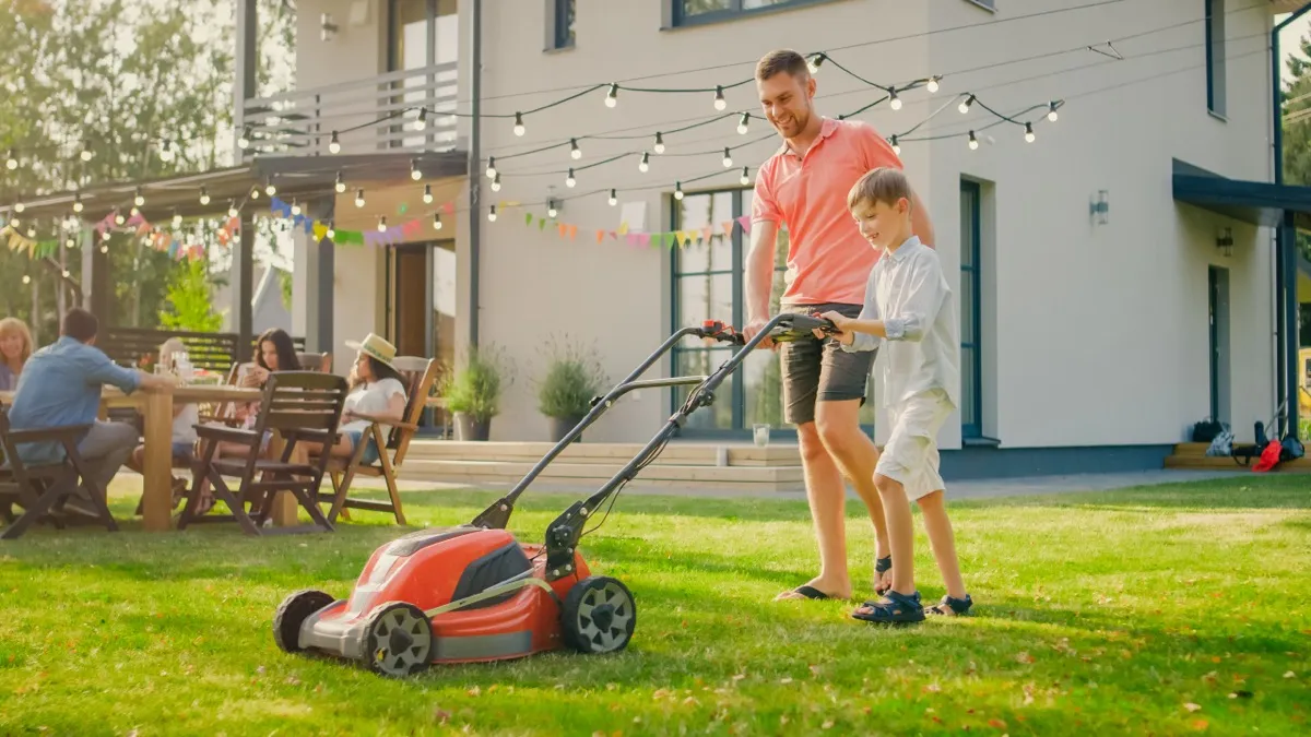 Father teaching his son to mow the lawn