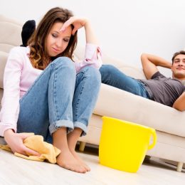 Man Watching TV While Woman Cleans