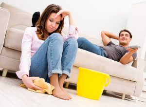 Man Watching TV While Woman Cleans