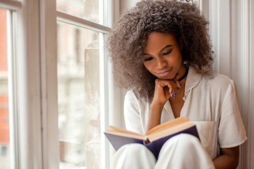 Young Black Girl Reading By the Window