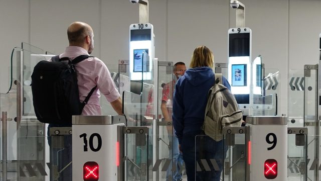 Passengers completing facial recognition at airport security checkpoint.