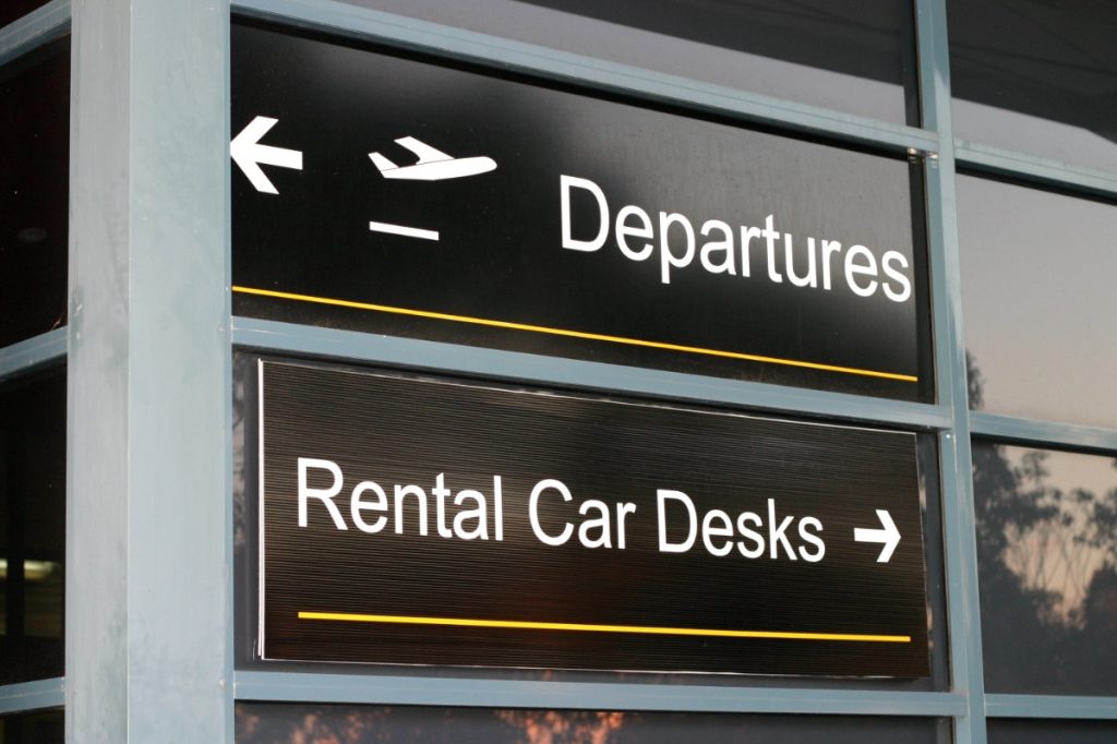 Signs pointing to airline departures and rental car desks.