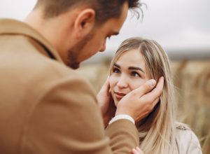 man being affectionate with his girlfriend in a field