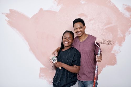 Shot of a young couple painting a wall pink.