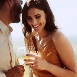 man whispering cute things to his girlfriend at a winery