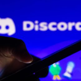 man using his phone in front of the Discord logo