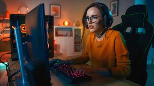 Excited Gamer Girl in Headset with a Mic Playing Online Video Game 