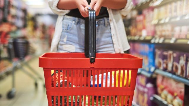 Shot of an unrecognizable woman holding a shopping basket at a grocery store