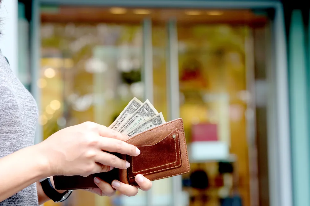 Cận cảnh một người rút ba tờ đô la từ ví của họ