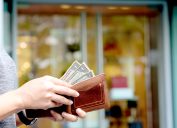 Cận cảnh một người rút ba tờ đô la từ ví của họ