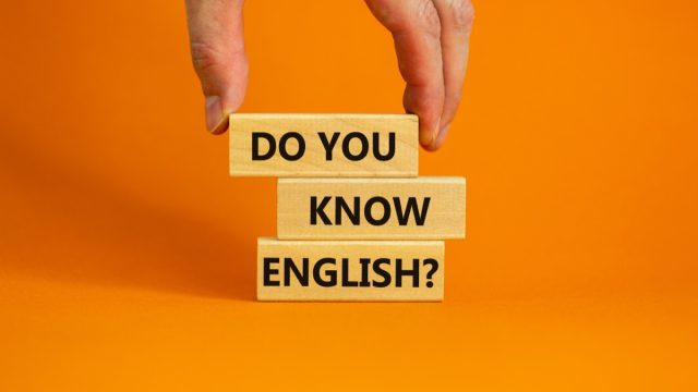 stack of blocks reading "do you know english" against an orange background