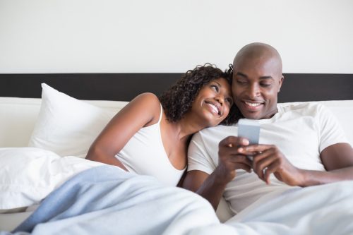 happy couple cuddling in bed reading good morning messages for him