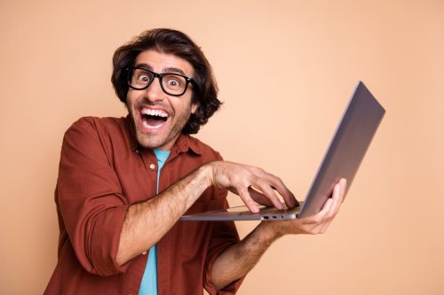 goofy man looking up dark jokes on his laptop