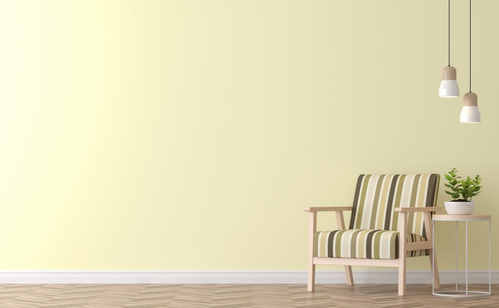 striped chair, side table with a plant, and two hanging lamps against gentle yellow wall