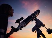 một cô gái trẻ nhìn bầu trời đêm bằng kính viễn vọng