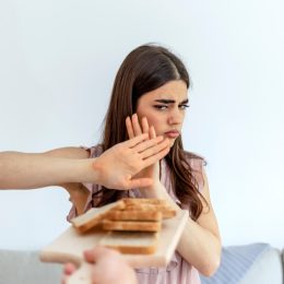 Cropped shot of a young woman on a gluten free diet is saying no thanks to white bread. Woman refusing to eat white bread.