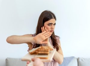 Cropped shot of a young woman on a gluten free diet is saying no thanks to white bread. Woman refusing to eat white bread.