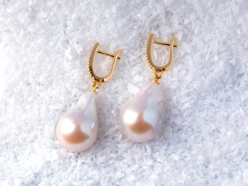 Luxury elegant baroque pearl earrings on white snow background.