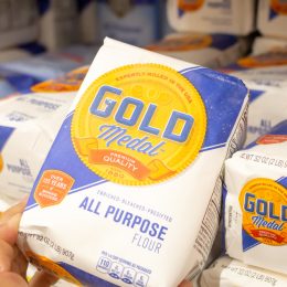 A closeup of someone holding up a bag of Gold Medal flour in the store