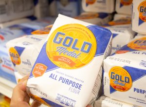 A closeup of someone holding up a bag of Gold Medal flour in the store