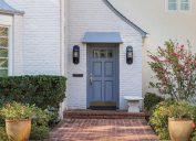 Cửa trước màu xanh của ngôi nhà theo phong cách truyền thống với lối vào bằng gạch và gạch trắng bên ngoài.