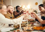 Nhóm người đa sắc tộc nâng ly ngồi bên bàn ăn tối tuyệt đẹp mừng Giáng sinh cùng bạn bè và gia đình, sao chép không gian