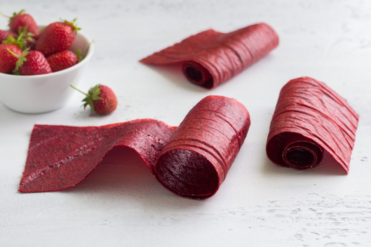 Homemade strawberry pastille with a bowl of fresh strawberries on a light blue background