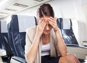 Một phụ nữ trẻ đang ngồi trên máy bay và bị đau đầu.