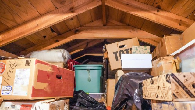 A pile of boxes and storage containers piled in an attic