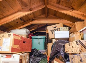 A pile of boxes and storage containers piled in an attic