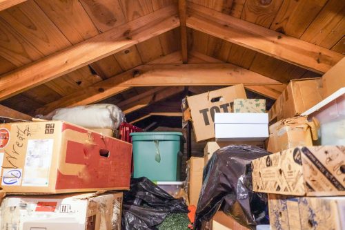 A pile of boxes and storage containers piled in an attic