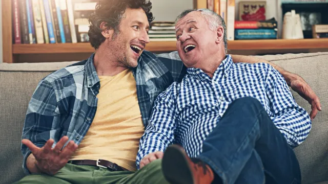 man sitting on the couch sharing funny knock-knock jokes with his father