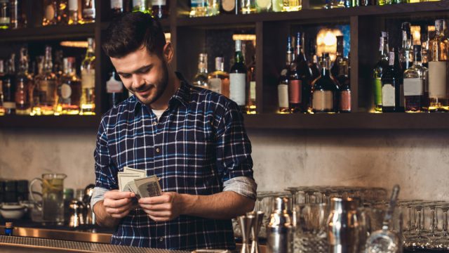 Male bartender counting money