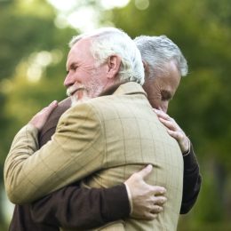 two mature men hugging