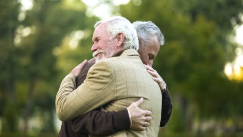 two mature men hugging