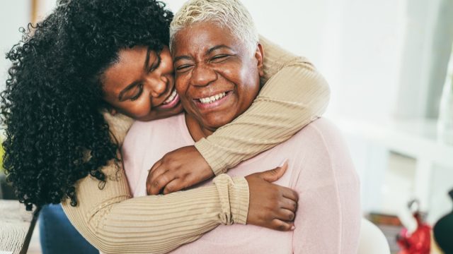 adult daughter hugging her mother, both smiling