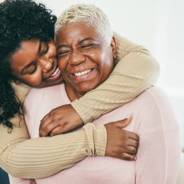 adult daughter hugging her mother, both smiling