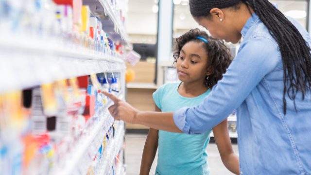 A woman and a young girl shop for OTC medicine in a pharmacy