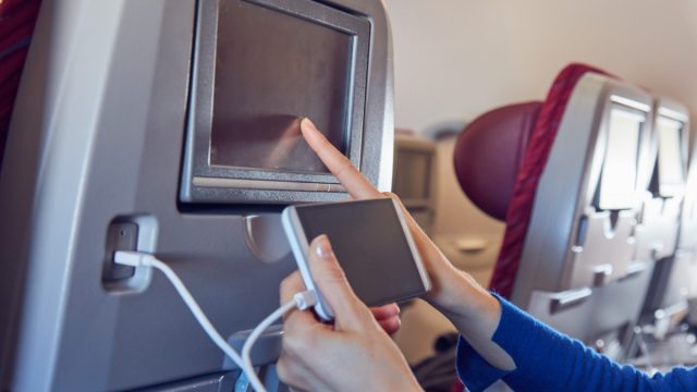 An airplane passenger charging their phone.