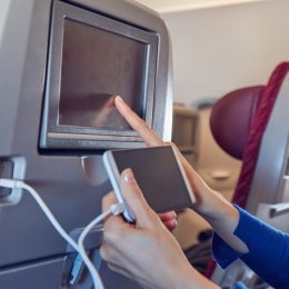 An airplane passenger charging their phone.