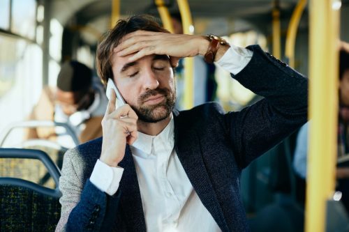 Một doanh nhân trung niên cảm thấy không hài lòng khi nói chuyện điện thoại di động và đi làm bằng xe buýt.