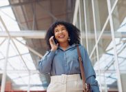 Phone call, smile or black woman travel in airport, office building or street for communication, networking or 5g network. London, tech or happy girl with smartphone walking, commute or travelling