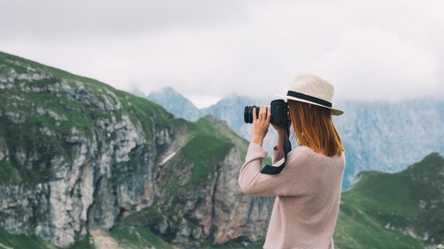 A woman taking a photo of mountain scenery.