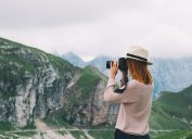 A woman taking a photo of mountain scenery.