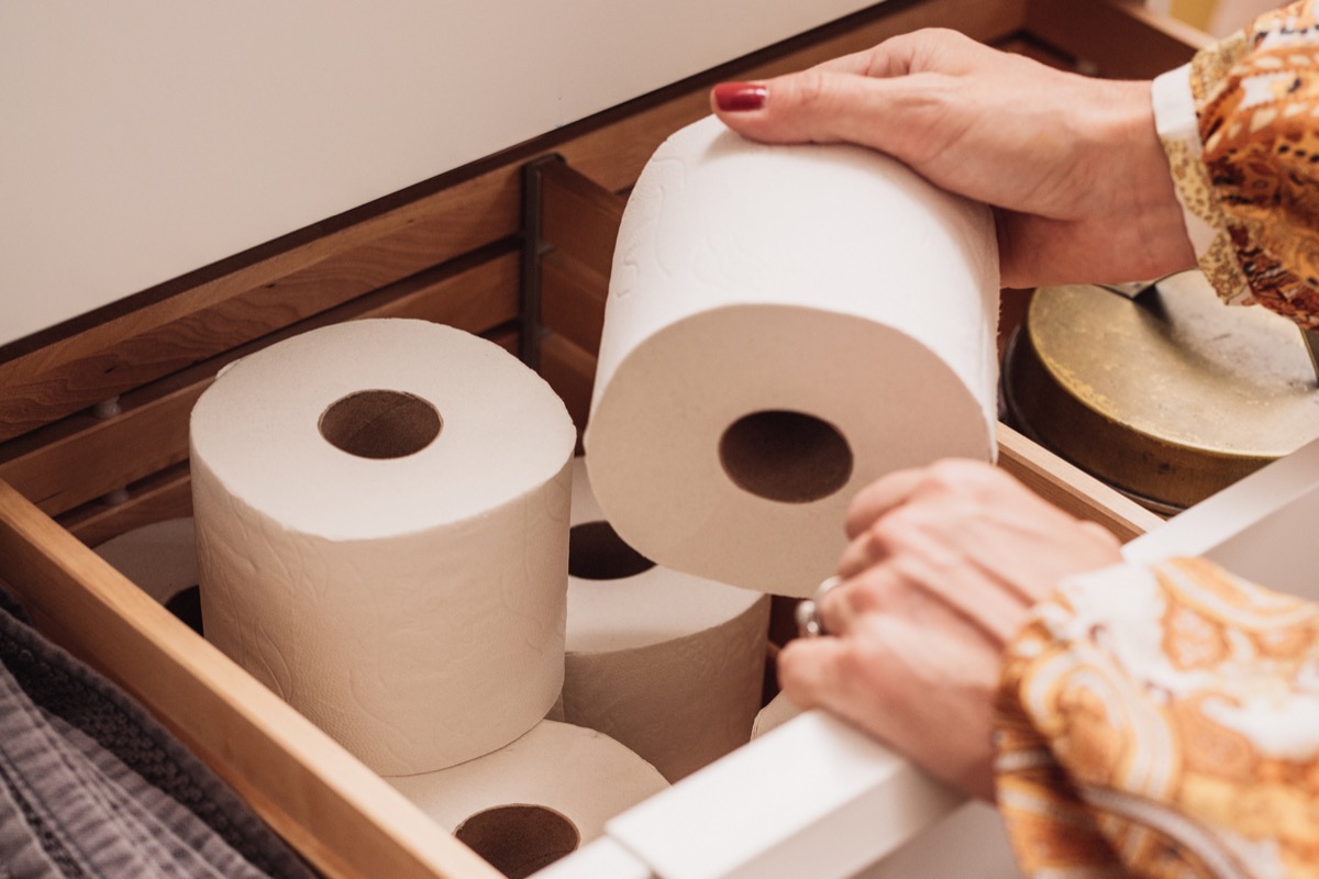 woman reaching for toilet paper from drawer