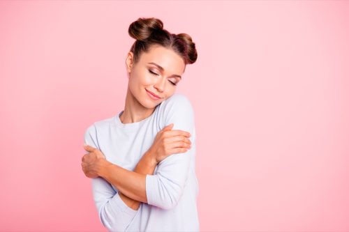 woman hugging herself over pink background