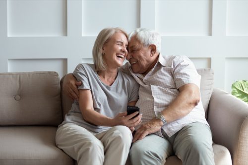 man and wife laughing and embracing on the couch