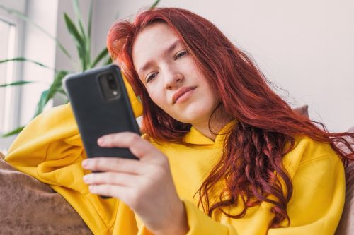 woman looking annoyed looking at her phone