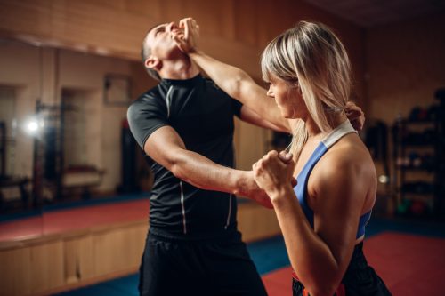 A female at a self-defense class, pushing her male instructor