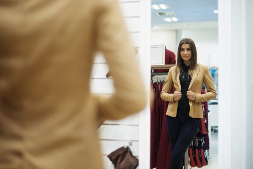 woman trying on jacket in fitting room